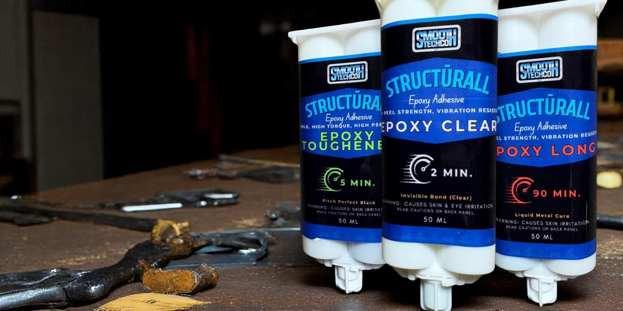 Three bottles of Structuráll epoxy adhesive on a workbench with tools in the background.