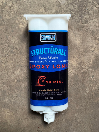 Epoxy adhesive tube labeled 'Structurall' on a concrete surface